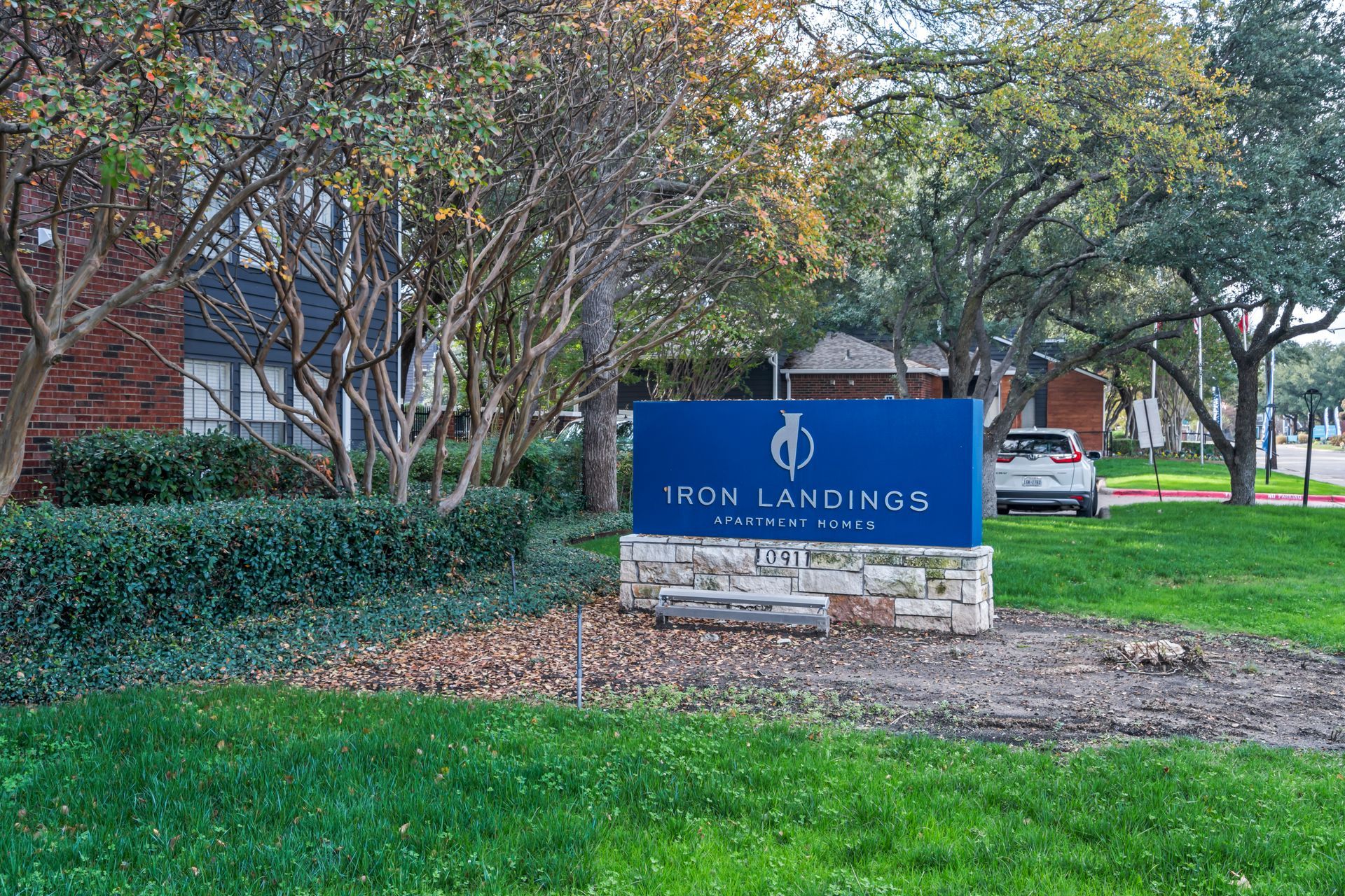 A blue sign is in the grass in front of a building.