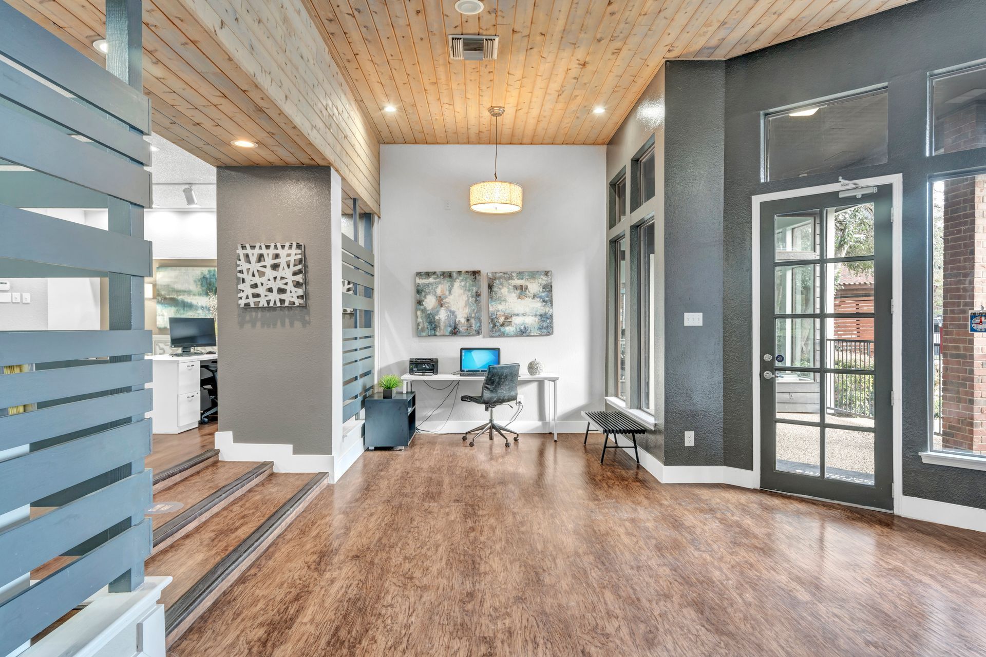 A large room with a wooden floor and a desk with a laptop on it.