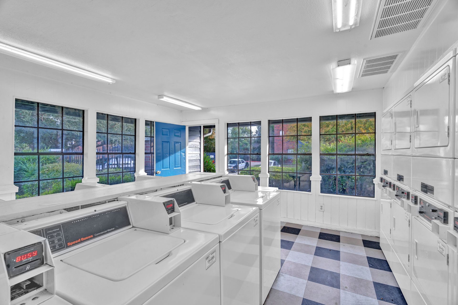 A laundromat with lots of washers and dryers and a checkered floor.
