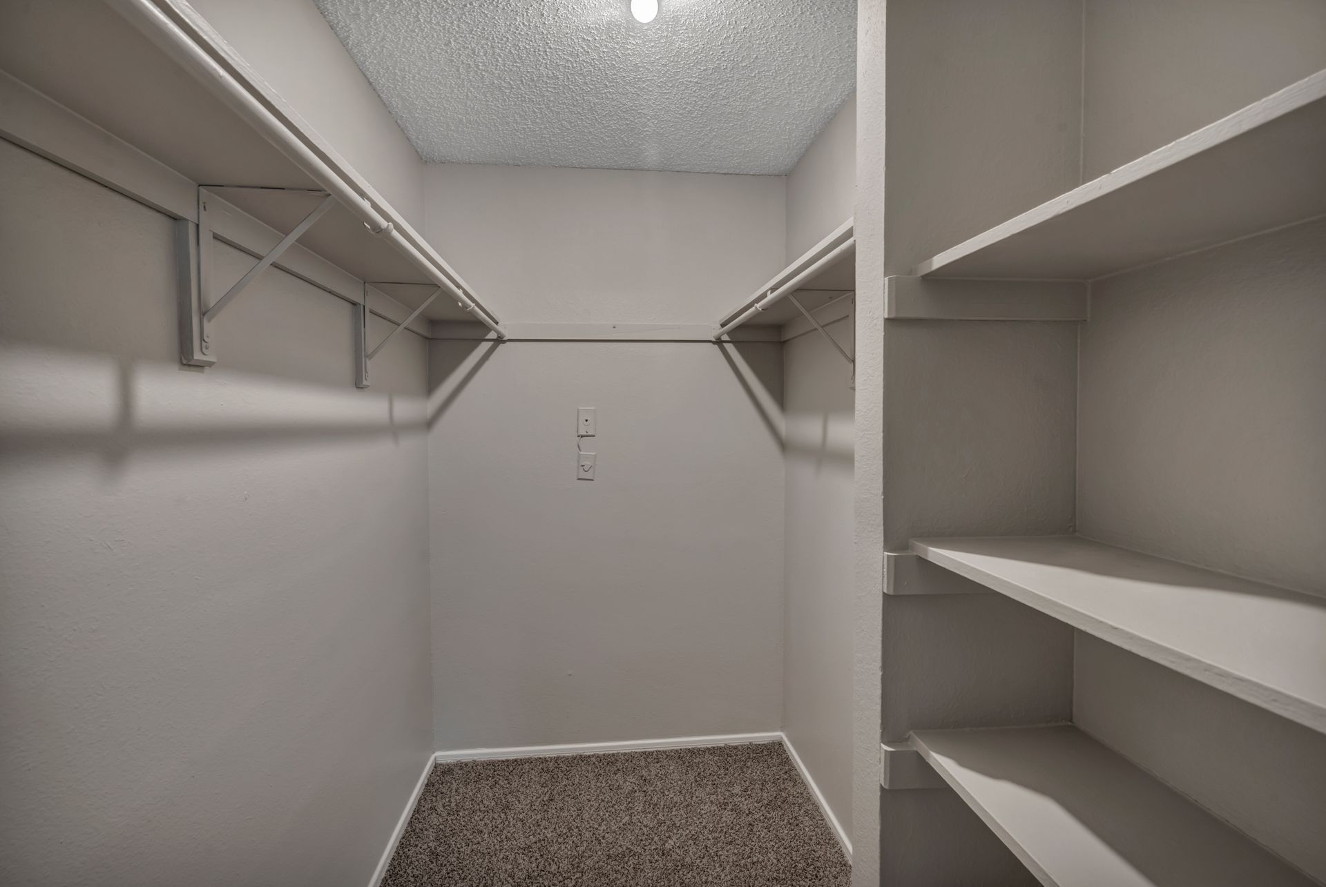 An empty walk in closet with lots of shelves and clothes racks.