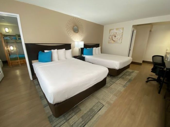 A hotel room with two twin beds, a desk, and a rug.