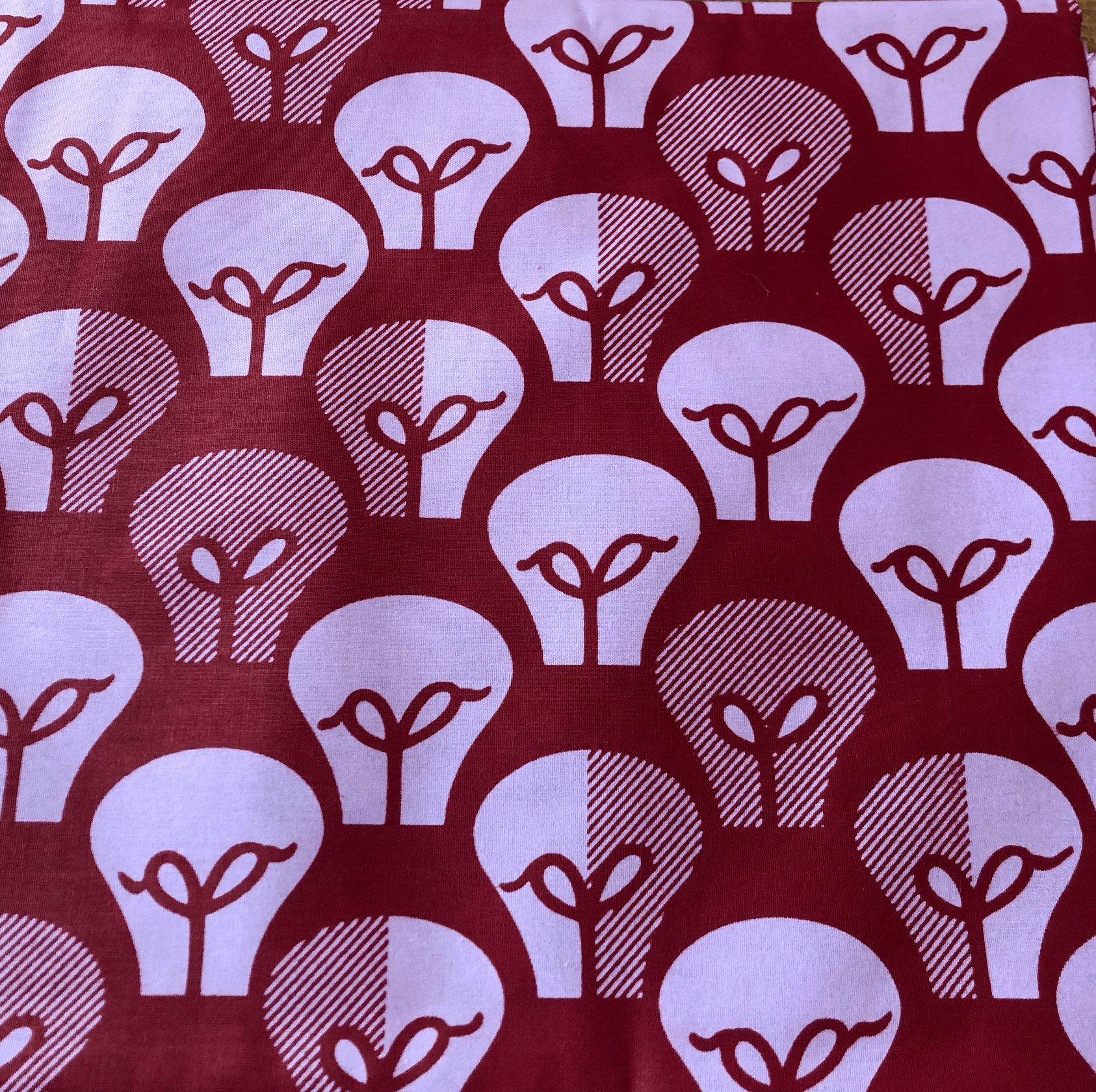 Tissu rouge avec un motif d'ampoules, alternant des moitiés pleines et hachurées.