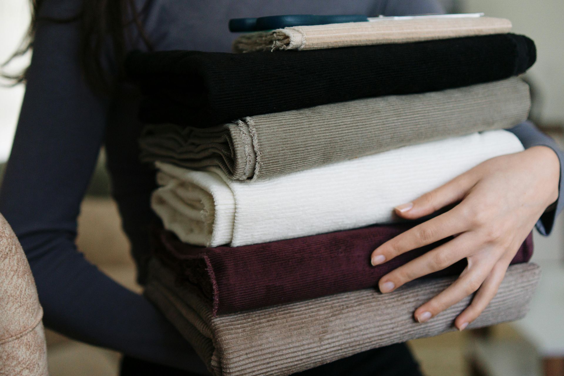 Personne tenant une pile de tissu plié de couleurs variées.