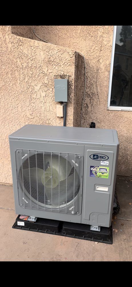 Air conditioning unit on black pads next to an exterior wall.