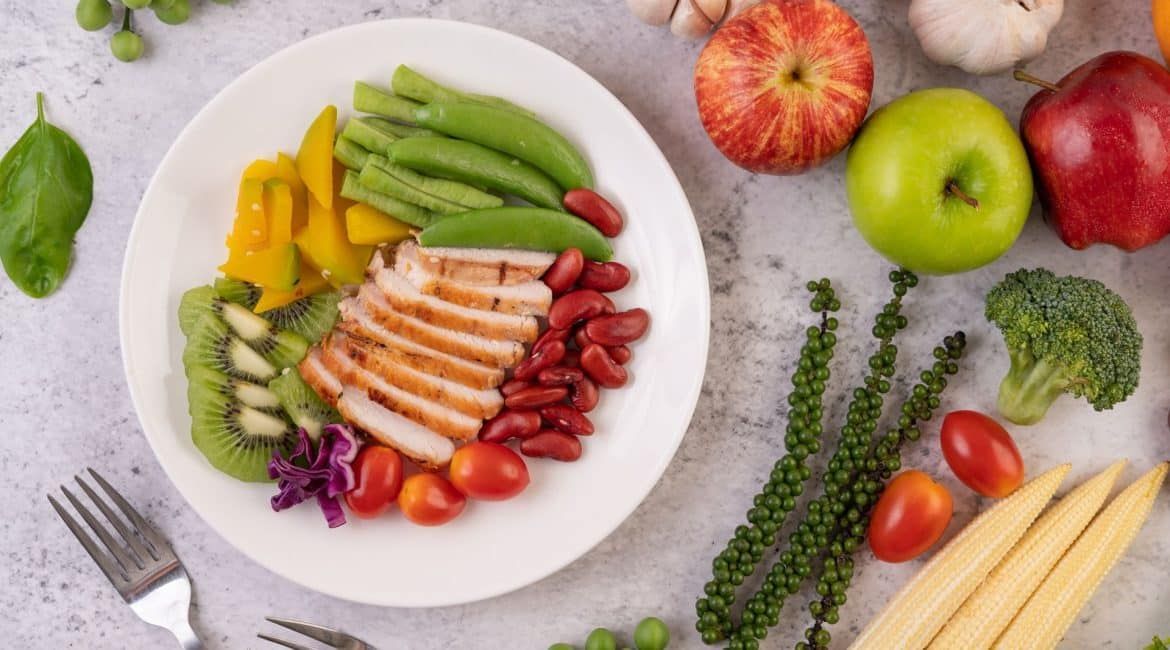 Colorful fruit and vegetable salad arranged on a white plate on a light stone surface