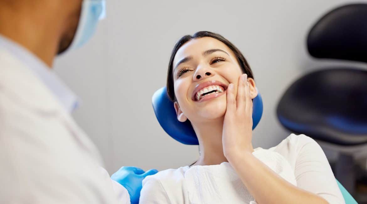 Patient smiling in a dental chair while a dentist examines her mouth
