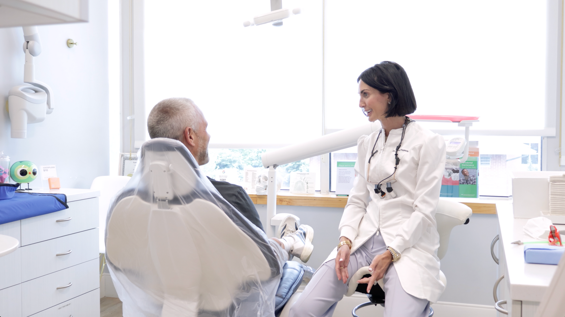 Smiling woman in a white robe flossing her teeth in a bathroom