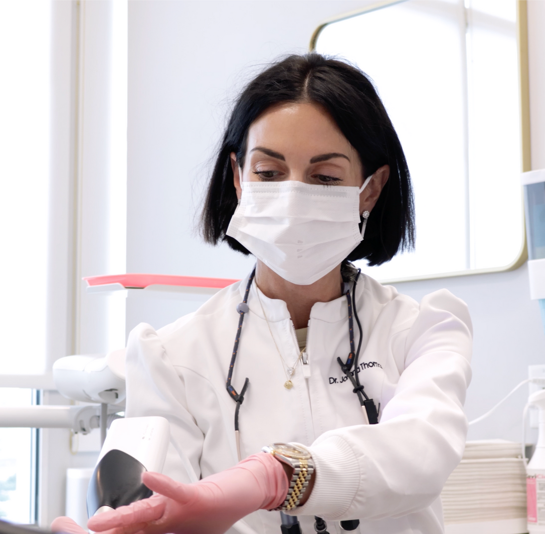 Man holding his cheek in a dental clinic, grimacing while staff in the background talk