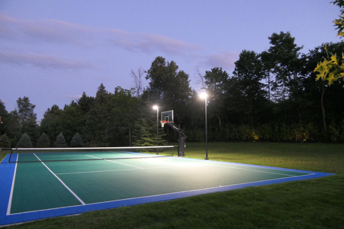 “Outdoor sport court glowing under evening lights with trees in the background during a court builder service in Tucson, AZ”