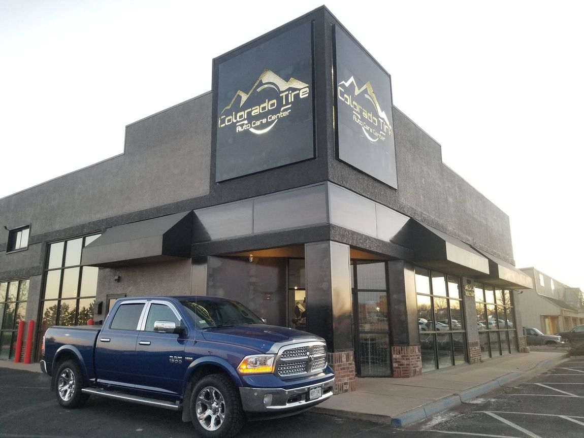 a blue car is parked in front of a tire store | Colorado Tire