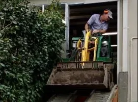 A man is driving a small bulldozer on a ramp. A man is driving a small bulldozer on a ramp.