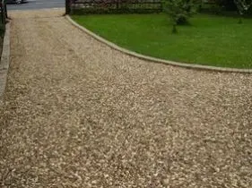 A gravel driveway leading to a lush green lawn. A gravel driveway leading to a lush green lawn.
