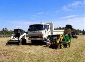 A dump truck and a bulldozer are parked in a field. A dump truck and a bulldozer are parked in a field.
