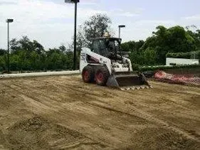 A bobcat is moving dirt in a field. A bobcat is moving dirt in a field.