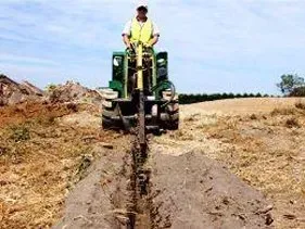 A man is driving a tractor through a muddy field. A man is driving a tractor through a muddy field.