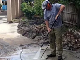 A man is using a high pressure washer to clean a sidewalk. A man is using a high pressure washer to clean a sidewalk.