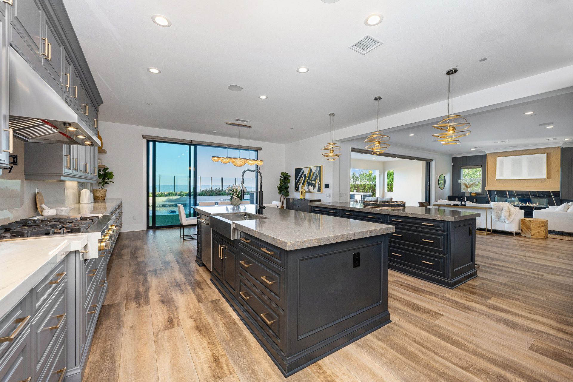 Modern kitchen with gray cabinets, wooden floors, and a large island.