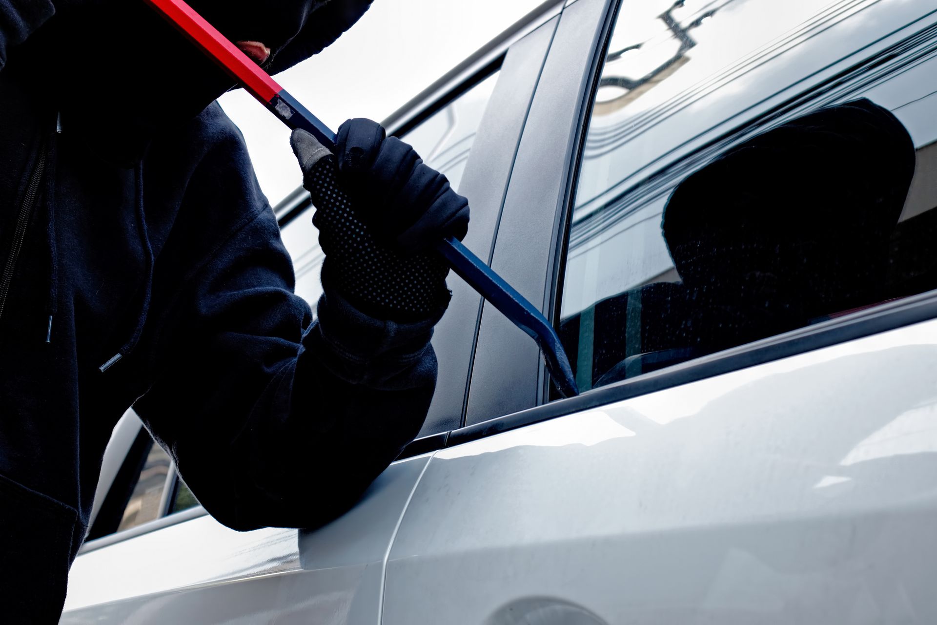 A man is working on a car door with a screwdriver A man is working on a car door with a screwdriver