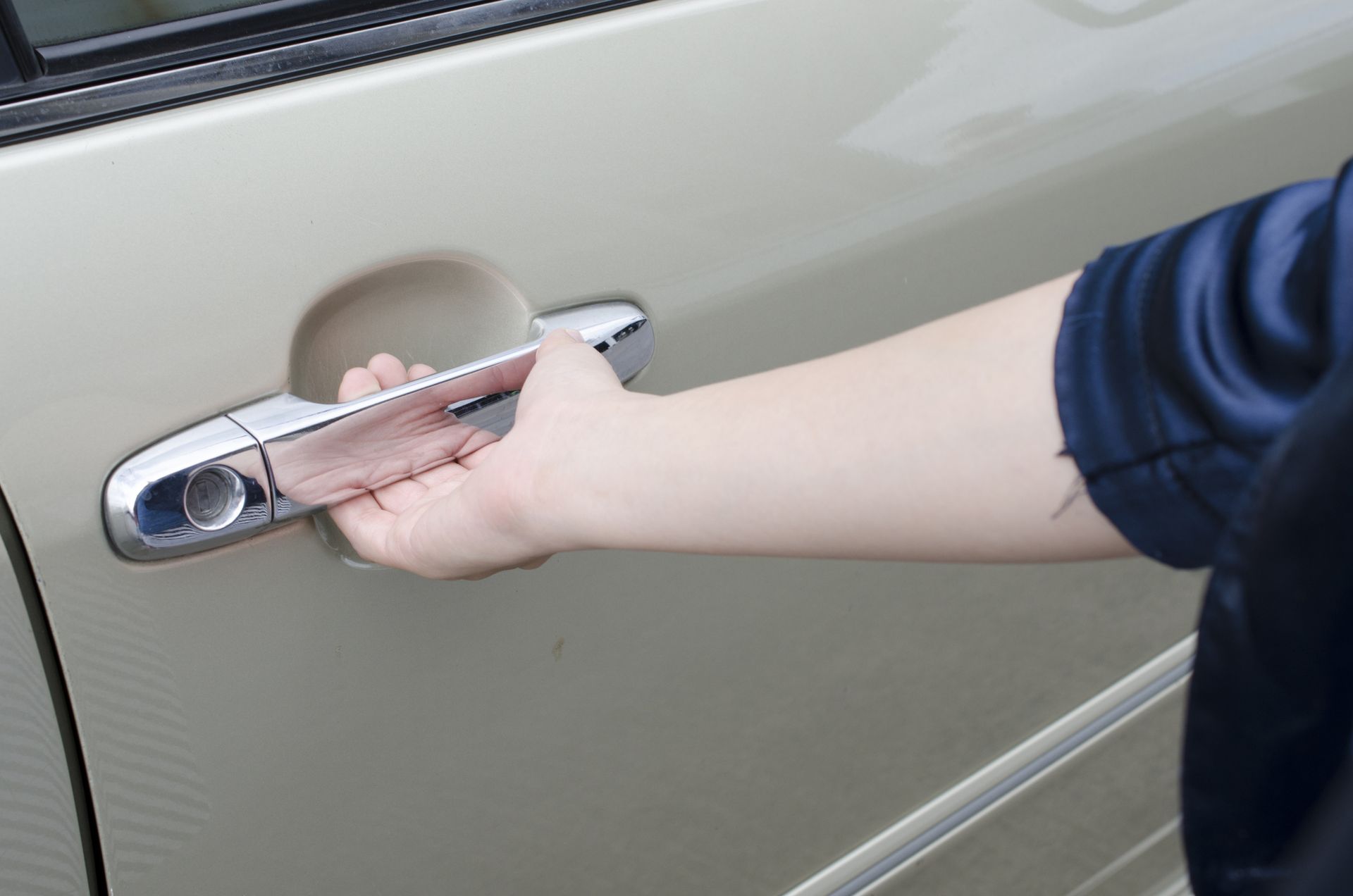 A person is opening the door of a car with their hand. A person is opening the door of a car with their hand.