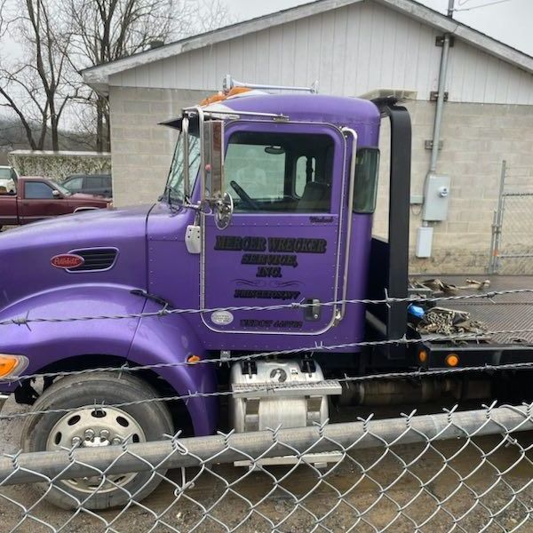 A purple tow truck is parked behind a chain link fence A purple tow truck is parked behind a chain link fence