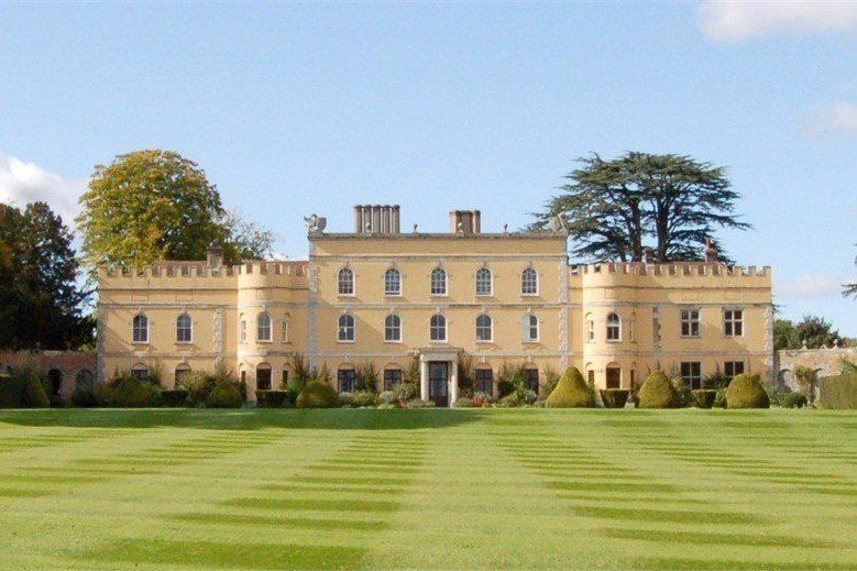 A large building with a lot of windows is surrounded by a lush green field