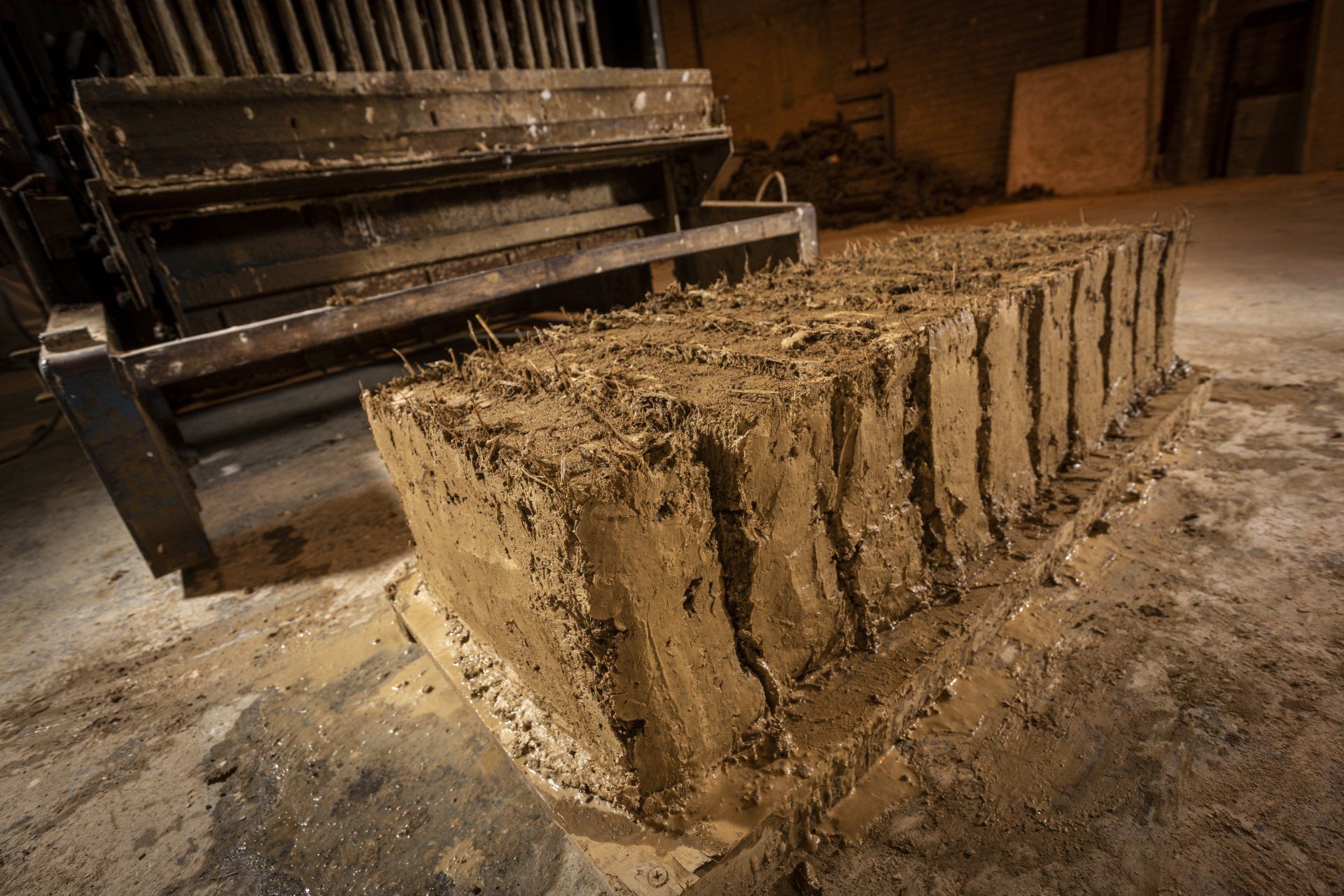 A pile of dirt is sitting on the ground next to a machine.