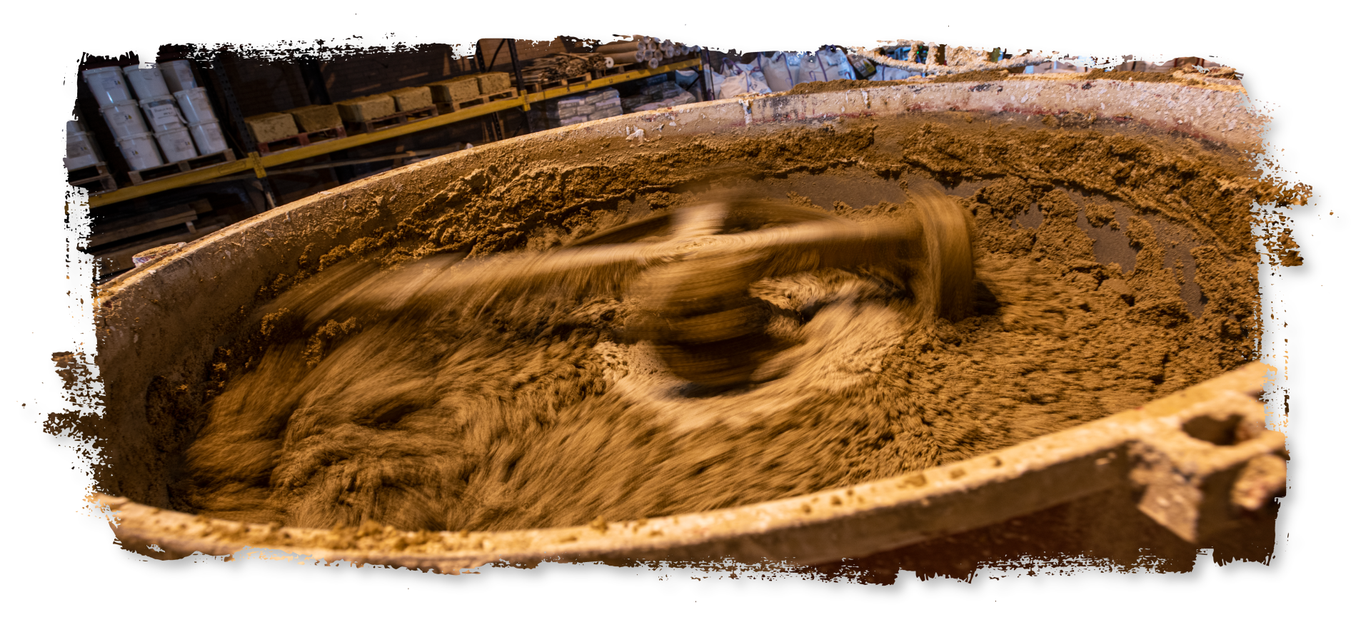 A large bowl of dirt is being mixed with a wooden spoon.