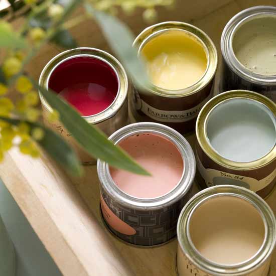 Several cans of paint are lined up on a table