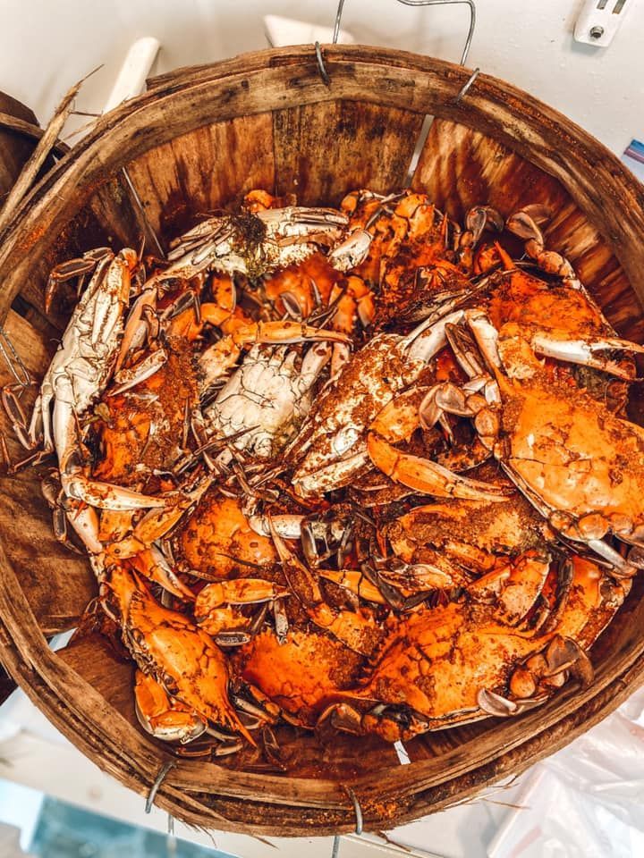 A bushel basket filled with steamed blue crabs seasoned with reddish-orange spices.