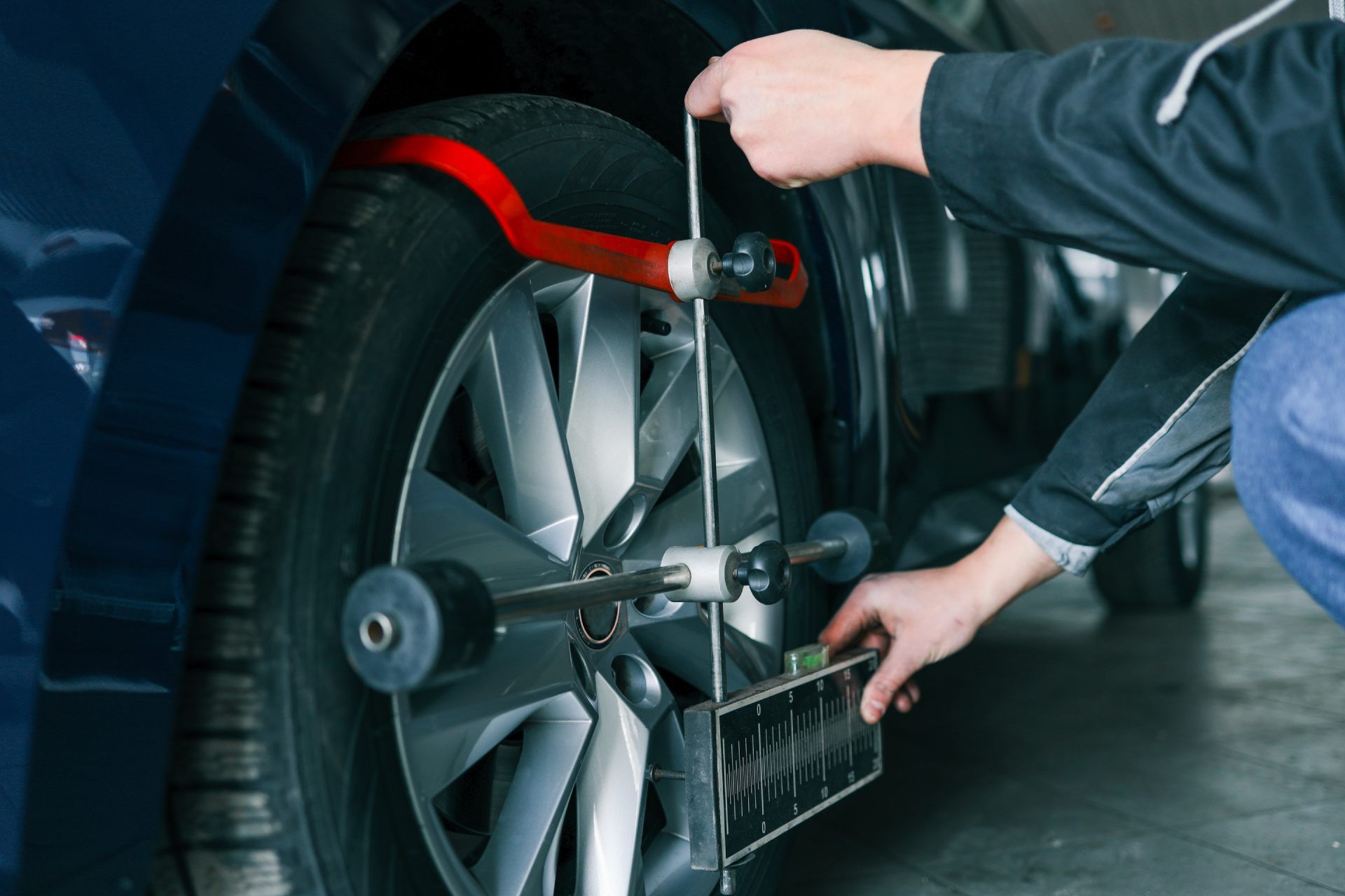Mechanic adjusting a car wheel with alignment tool in a garage.