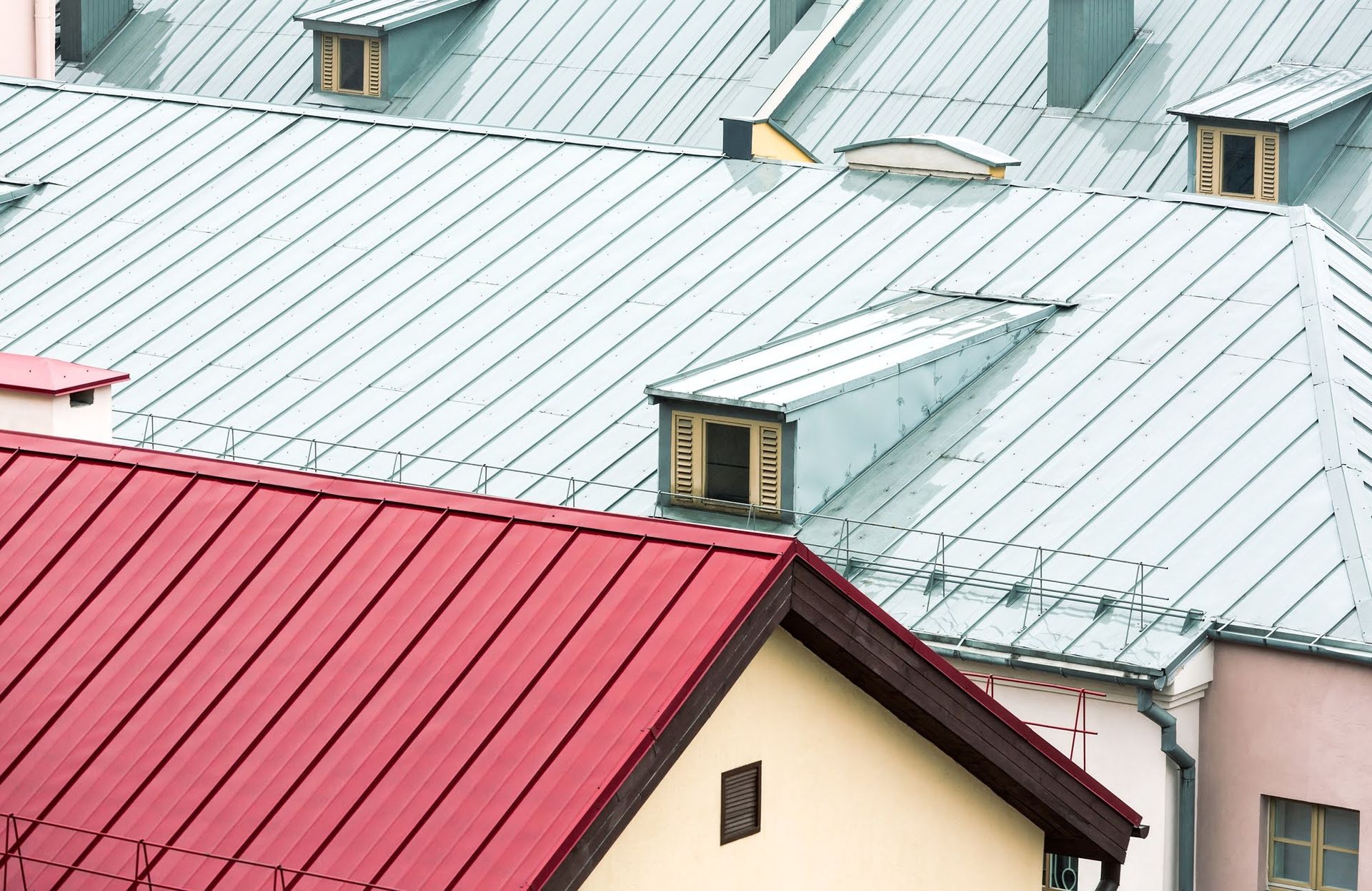 Roofs of buildings with red and gray metal, with dormers.
