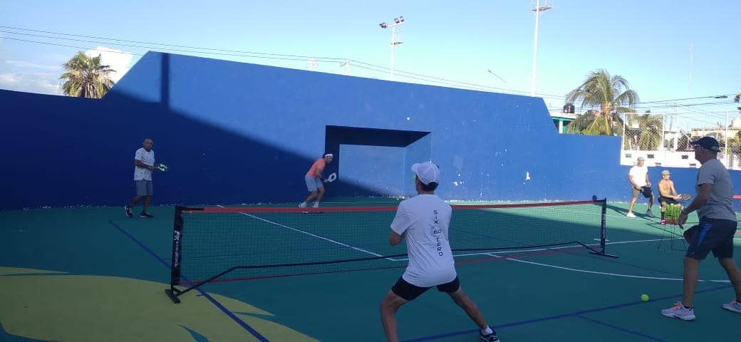 A group of people are playing pickleball on a court at the Playa Del Carmen Pickleball Club in Playa Del Carmen, Mexico 