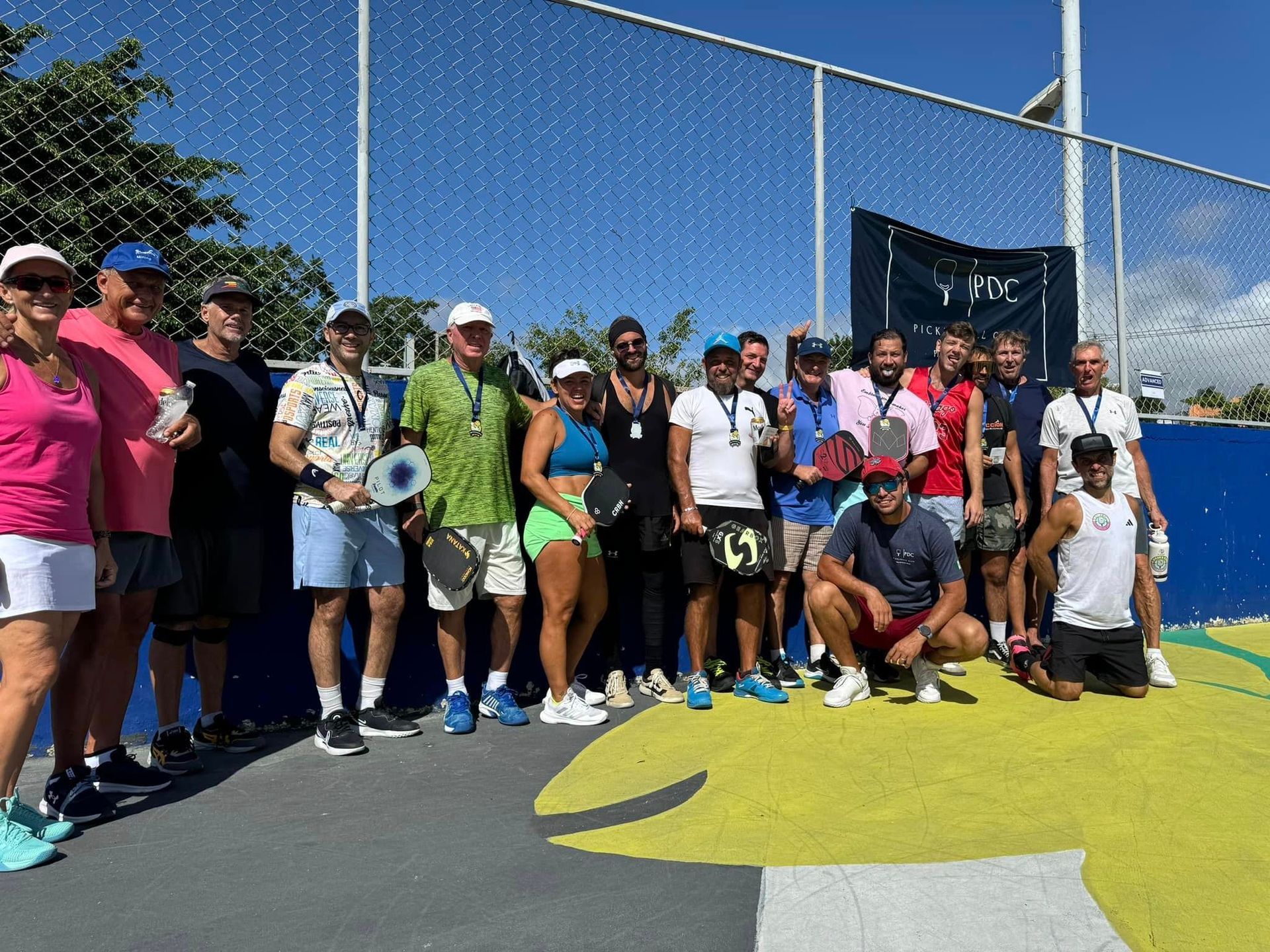 A group of people are posing for a picture on a tennis court.