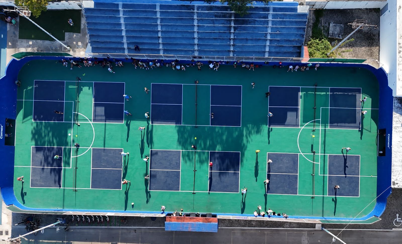 A group of people are playing tennis on a pickleballcourt