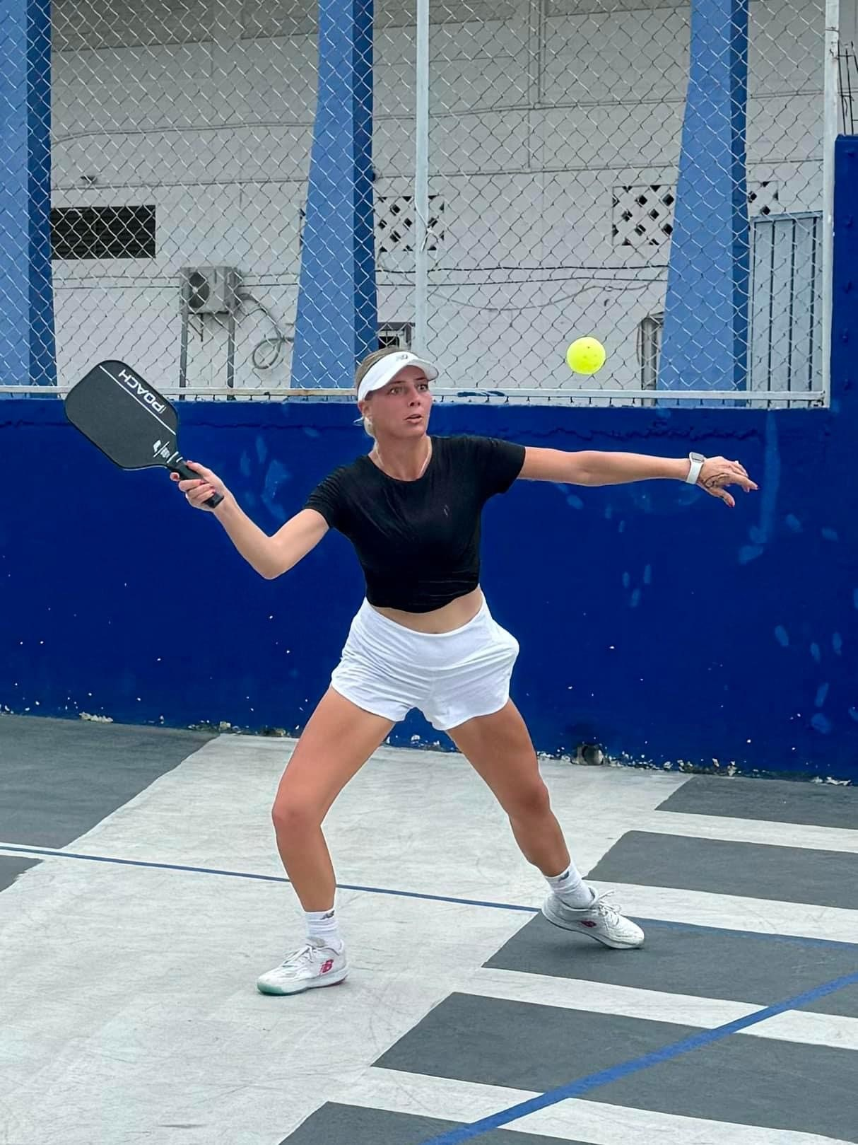 A woman is playing a game of pickleball on a court at the Playa Del Carmen Pickleball Club in Playa Del Carmen, Mexico