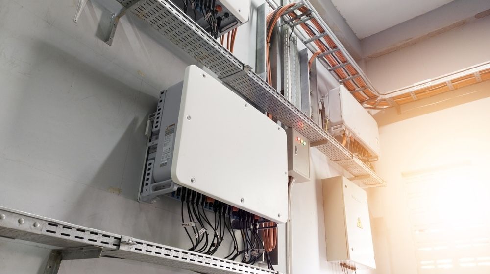 A Battery With Two Wires Attached to It is Sitting on a Wooden Floor — Ray Smith Electrical in Grafton, NSW