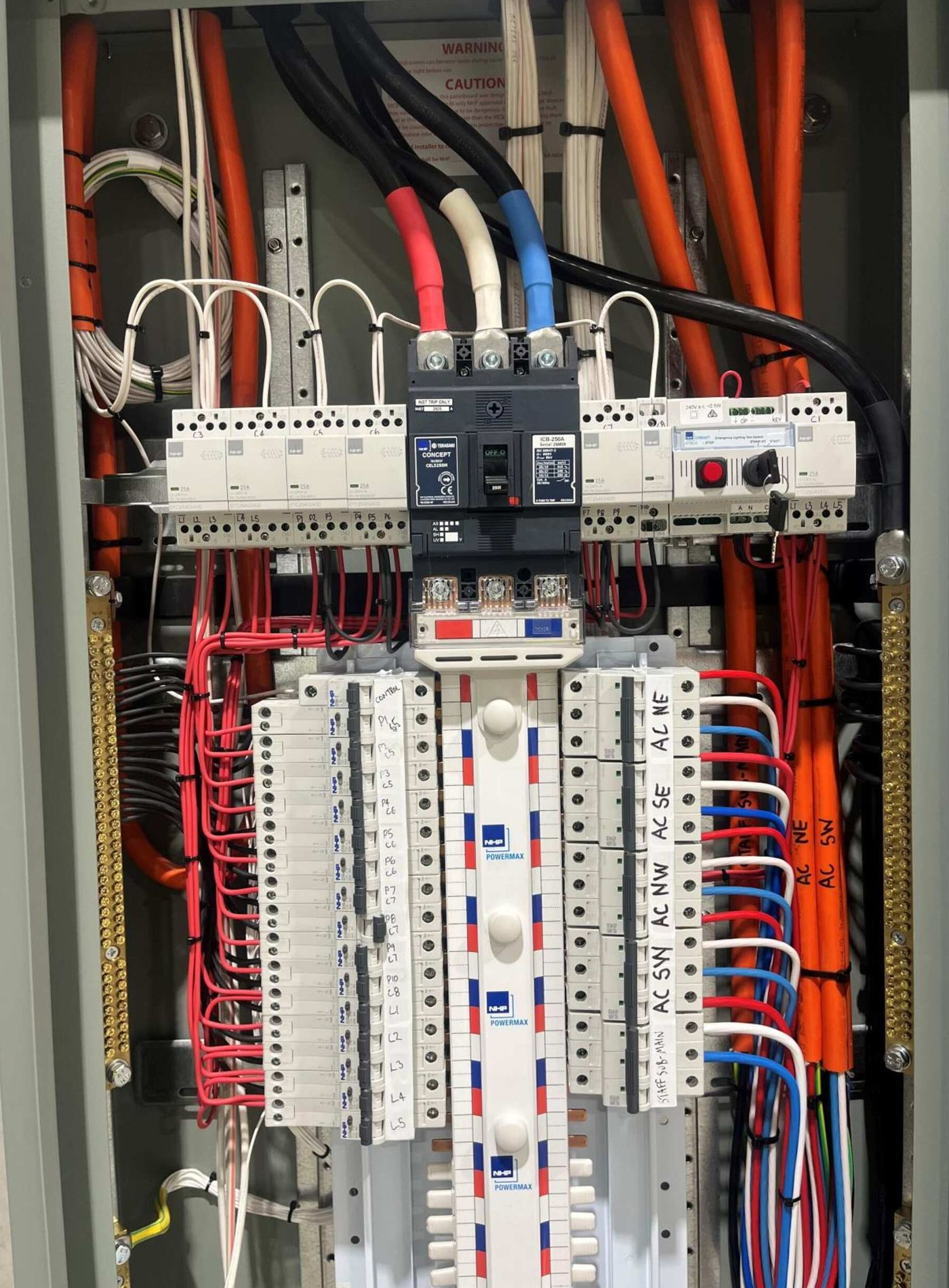 Electrical panel with wires and circuit breakers; orange, red, blue, and white wires visible— Ray Smith Electrical in Korora, NSW