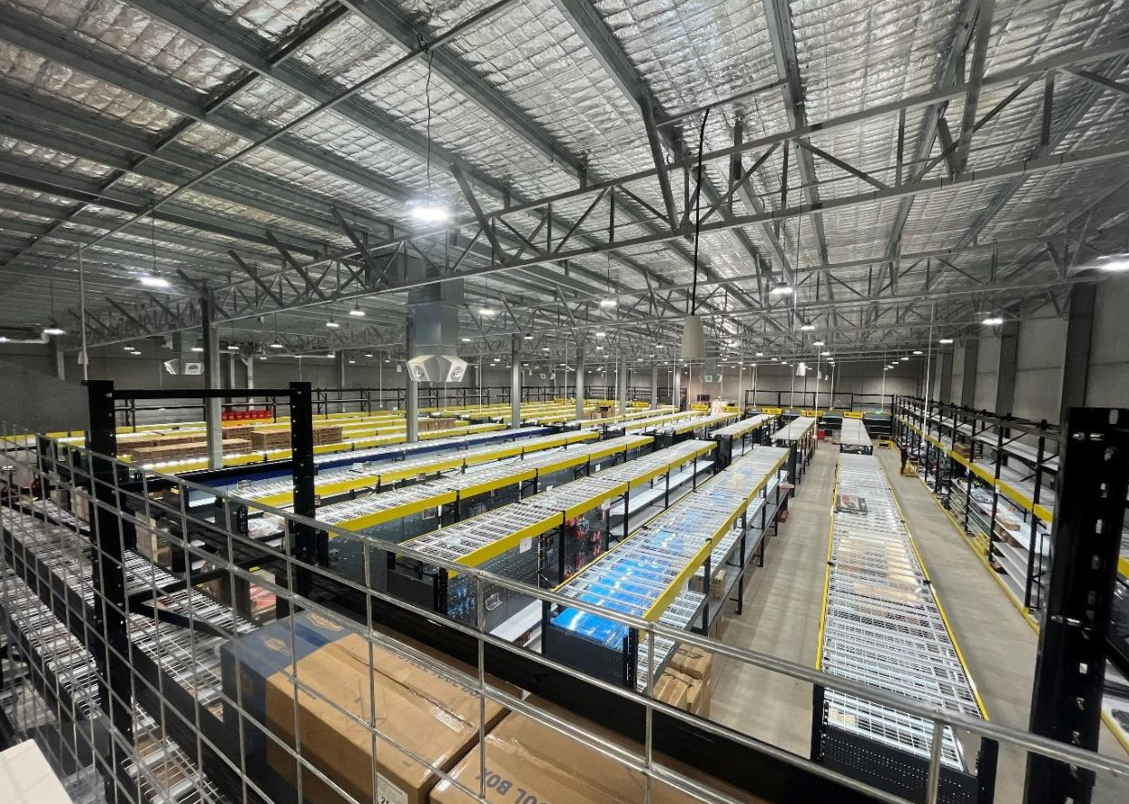 Large warehouse interior with rows of storage shelves, goods, and overhead lighting— Ray Smith Electrical in Korora, NSW