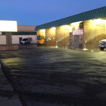 Car wash at dusk with spraying bays, empty lot, and sign.