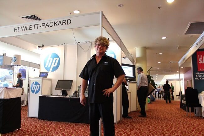 Man in Black Uniform Stands in Front of A HP Booth at A Conference — Rme in Sapphire, NSW