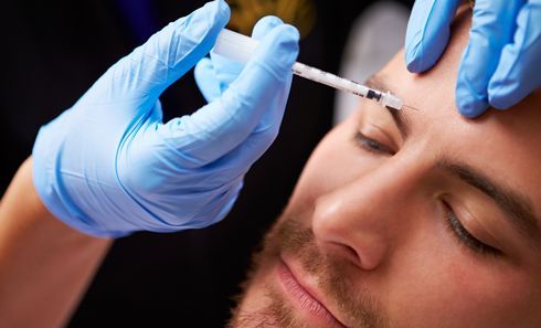 A man is getting a botox injection in his forehead.