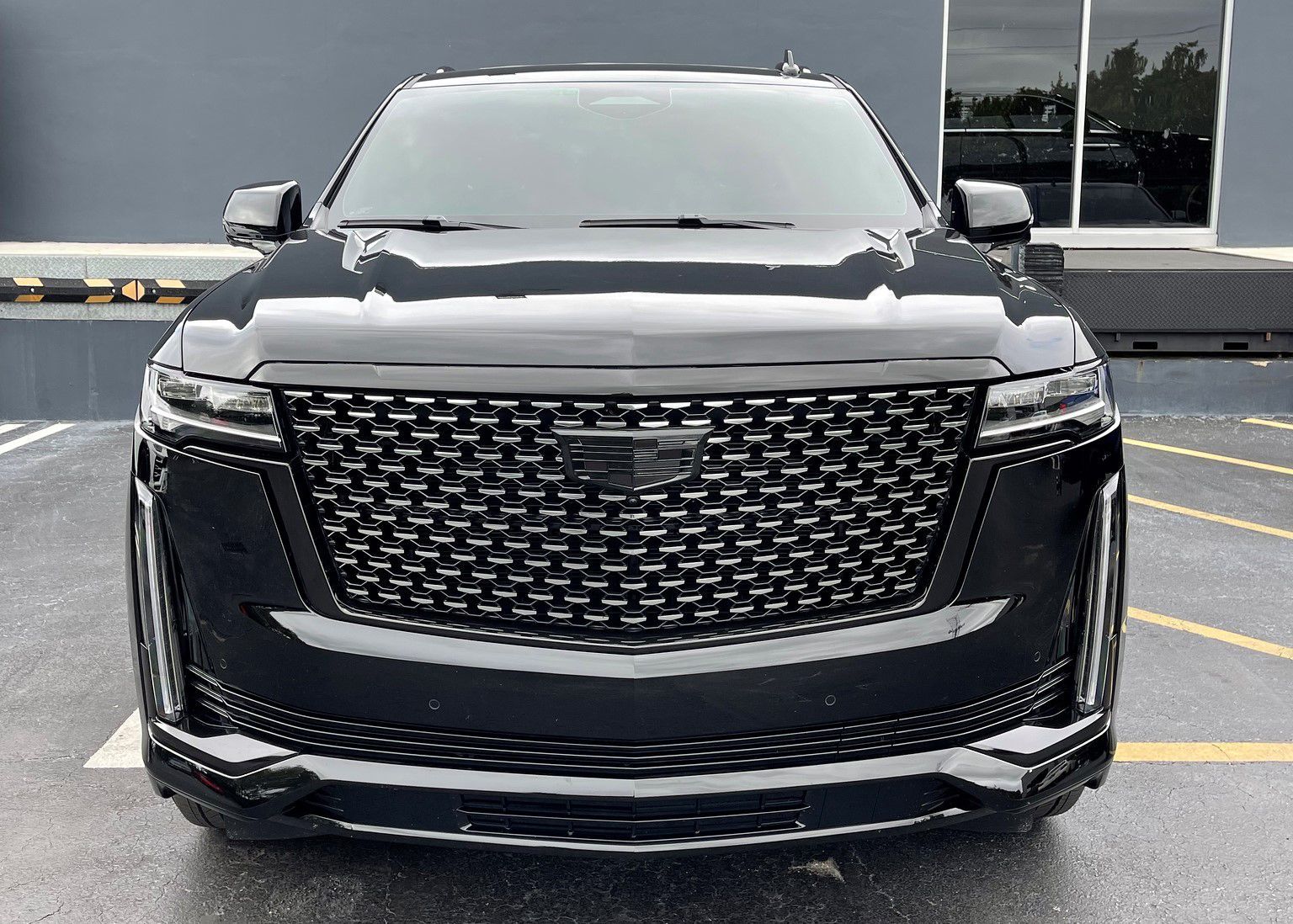 A black Cadillac Escalade is parked in a parking lot.