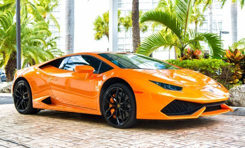An orange Lamborghini Huracan is parked in front of a building.