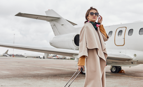 A woman is talking on a cell phone in front of a private jet.