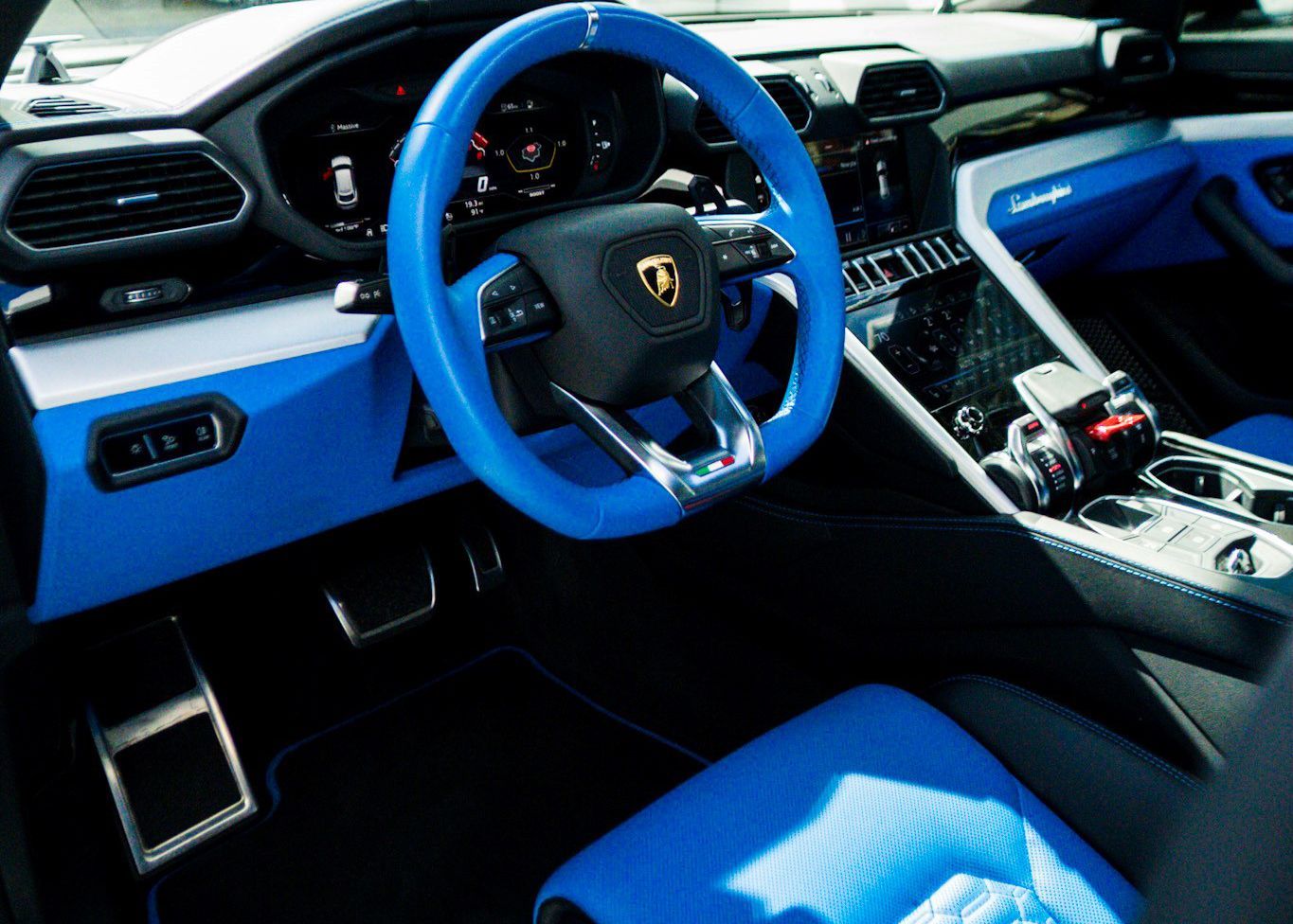 The interior of a Lamborghini with blue seats and a blue steering wheel.
