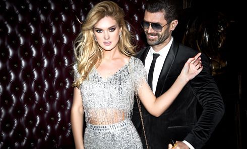 A man in a suit and tie is standing next to a woman in a silver dress.