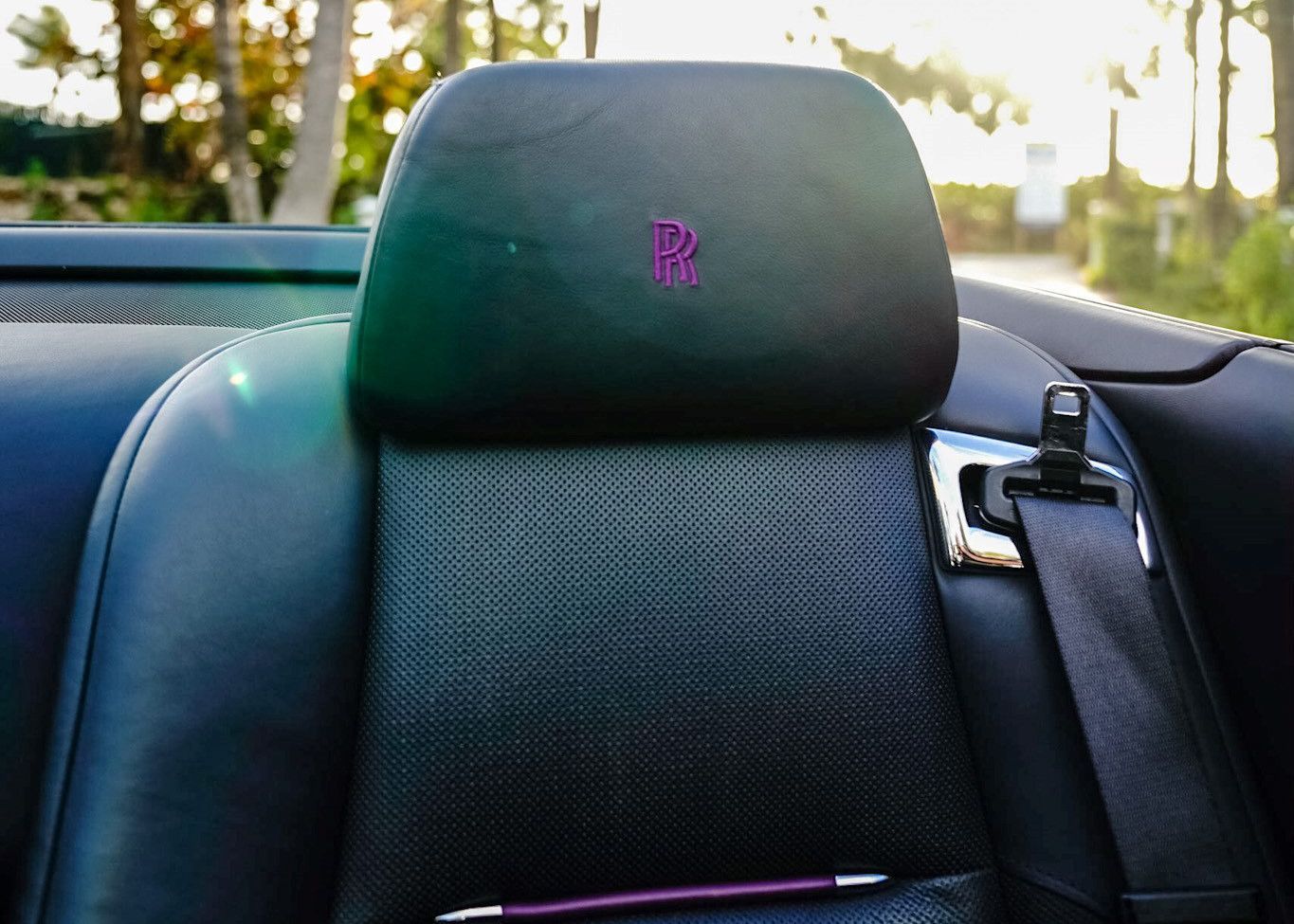 A black car seat with a purple letter R on it.