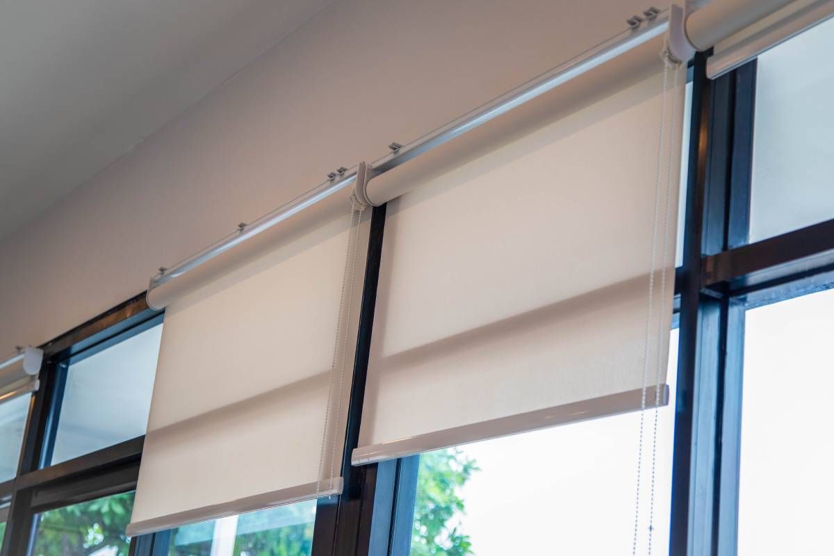 Modern office with white roller shades covering a row of windows.