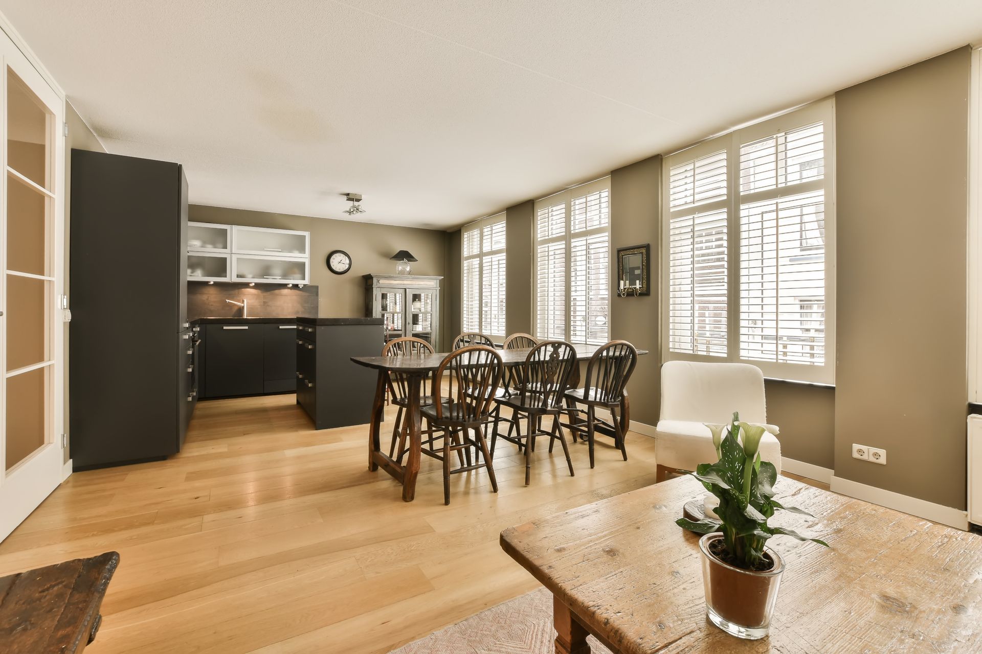 Modern open concept kitchen with wood shutters and dining table. 