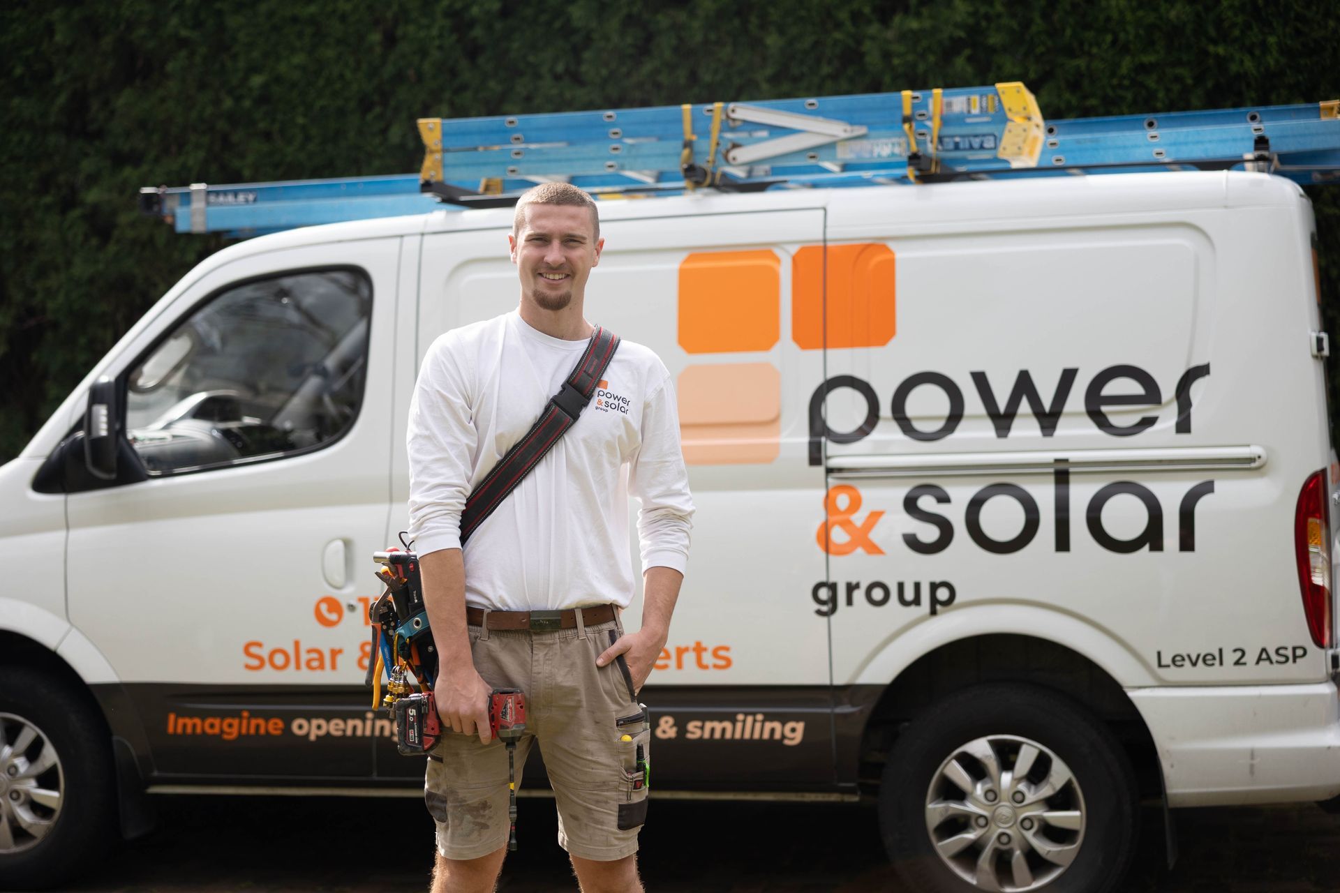 Man standing beside a white Power & Solar service van with ladder on roof